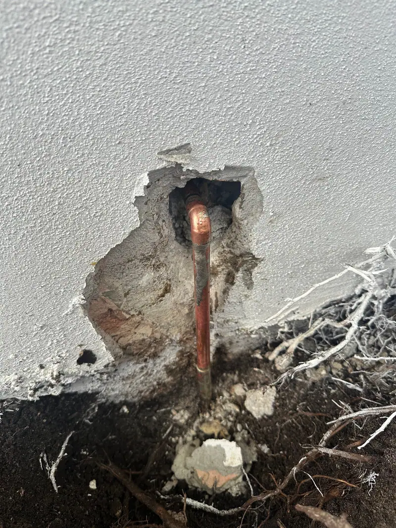 Copper pipe coming out of a stucco wall where a leak was opened up and repaired