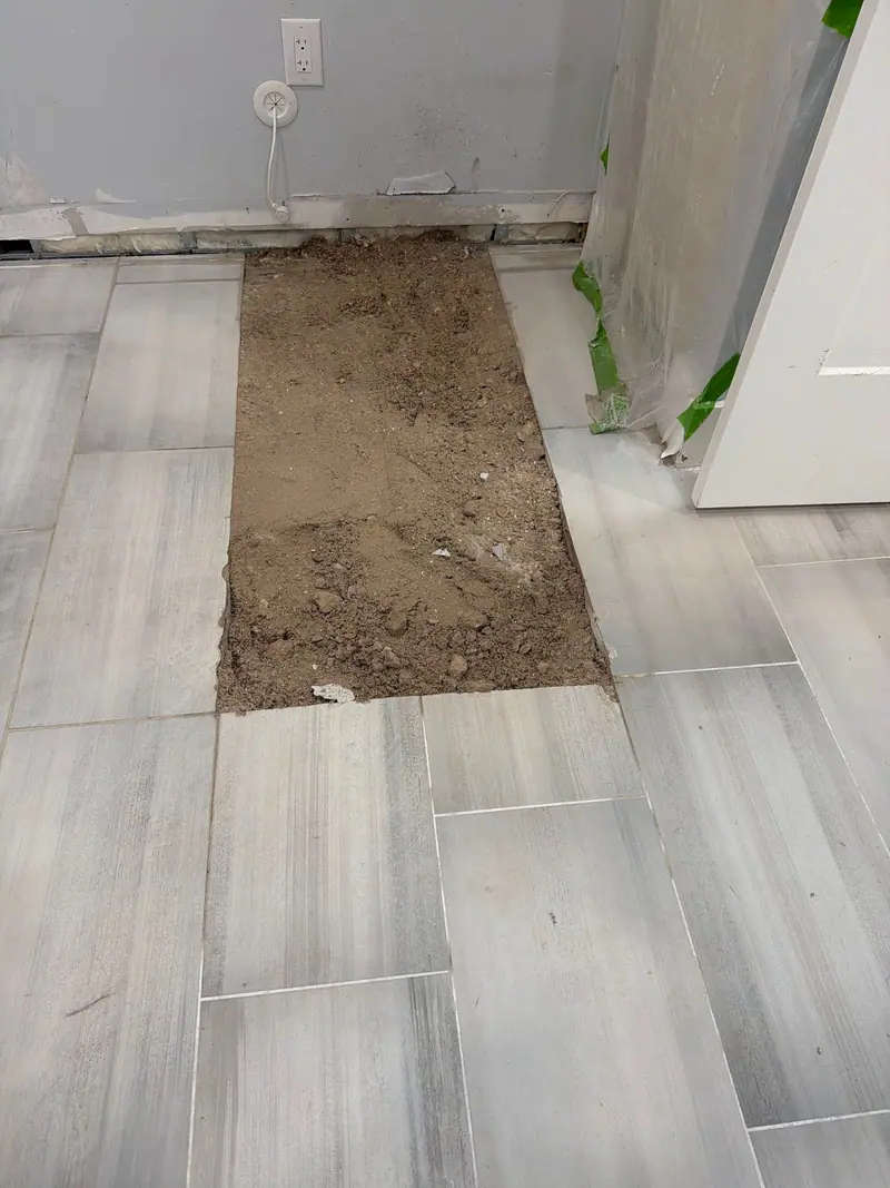 Plank tile floor opened along a line to reach the pipe underneath