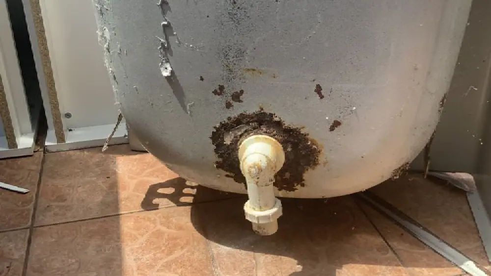 Rust around the drain valve at the base of an old water heater tank