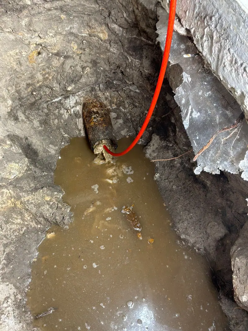 Muddy dig down to a leaking line, the water pooling in the hole