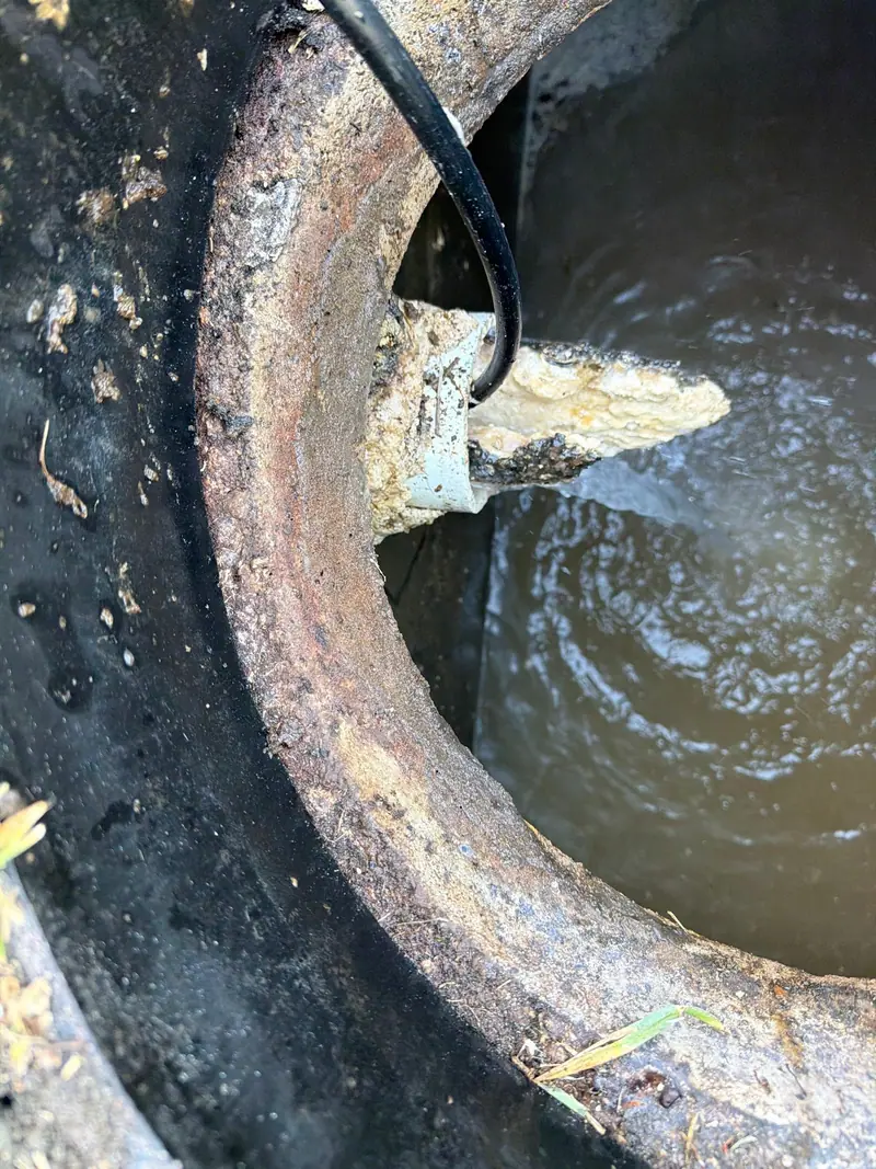 Looking into a corroded cast-iron pipe with standing water inside