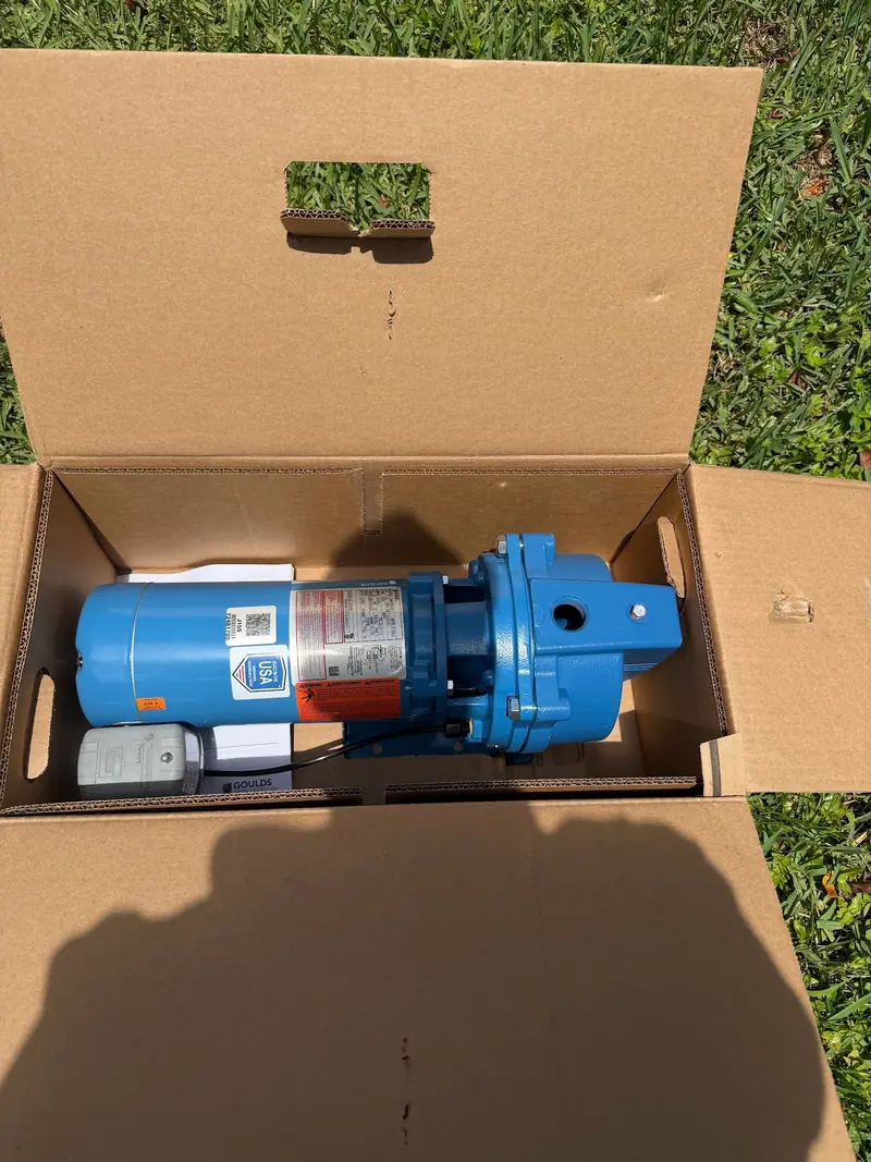 A new blue jet pump in its carton on the lawn, ready to go in