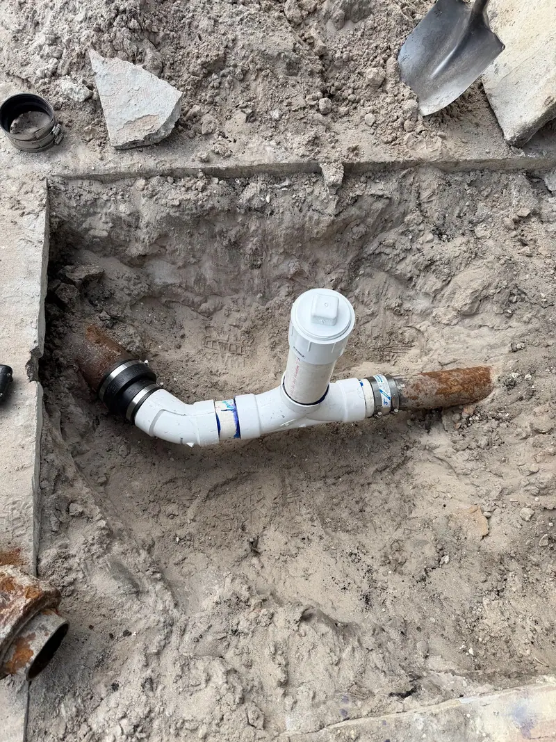 New white PVC elbow and cleanout bedded in sand
